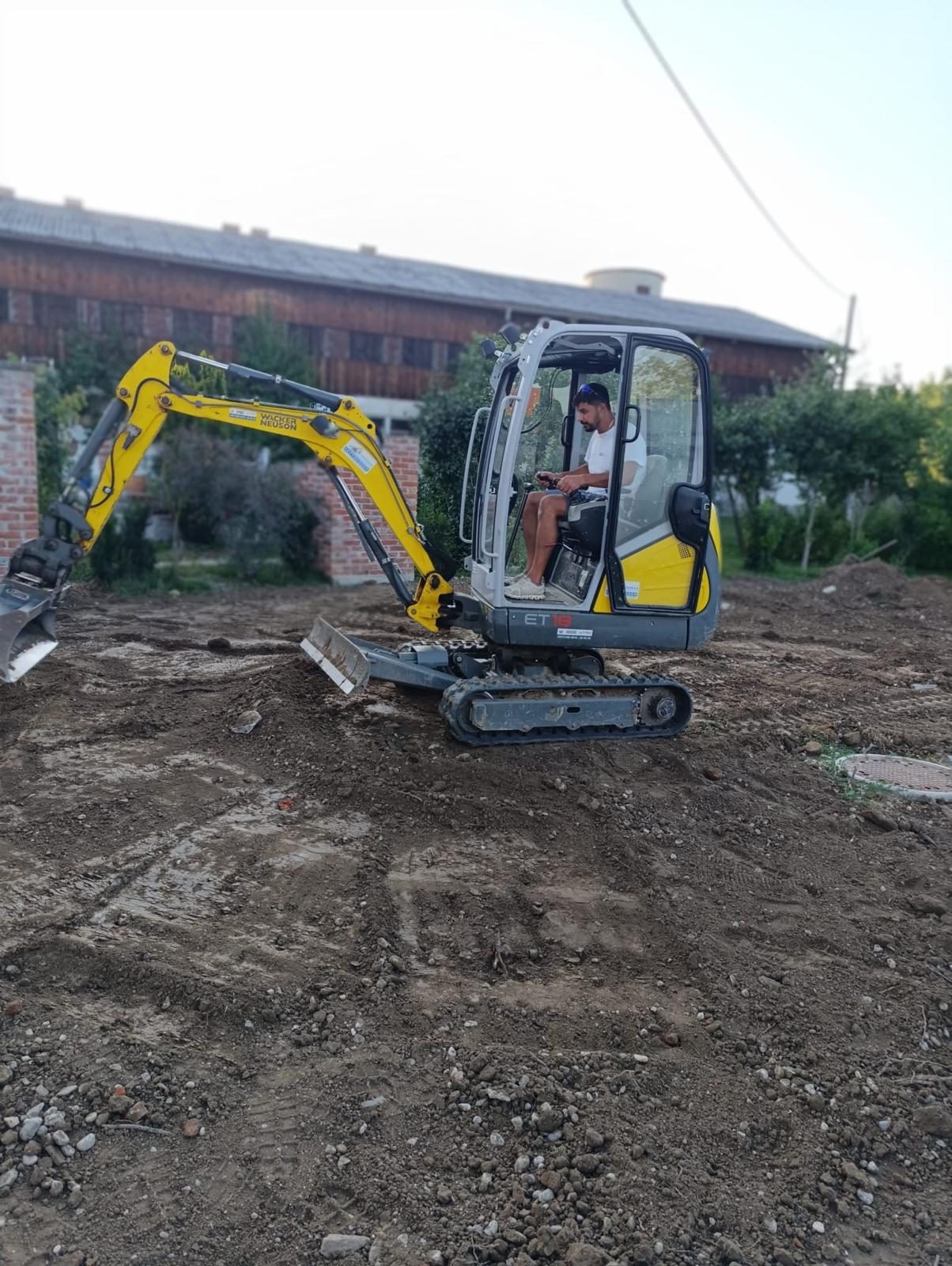 Mitarbeiter im Minibagger beim Ausheben der Poolgrube
